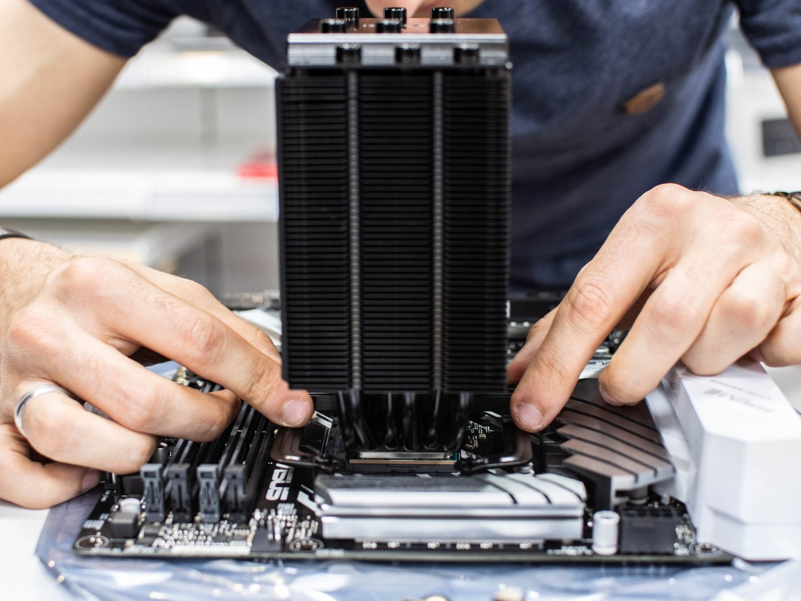 Techniker montiert einen CPU-Kühler auf einem Mainboard